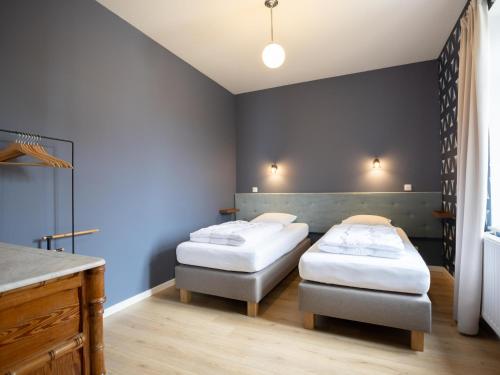 two beds in a room with blue walls at Woonhuys in Riemst