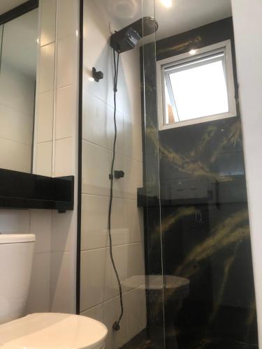 a bathroom with a shower with a toilet and a window at Flat Red Sorocaba- Green in Sorocaba