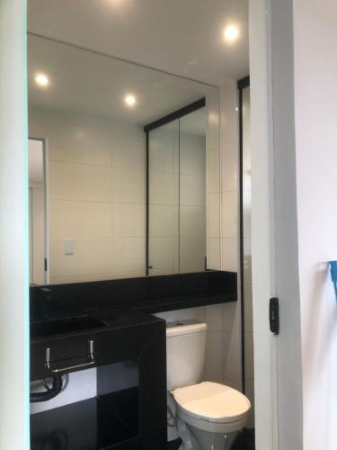 a bathroom with a toilet and a large mirror at Flat Red Sorocaba- Green in Sorocaba