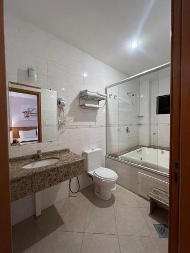 a bathroom with a toilet and a sink and a tub at Hotel Dom Leopoldo in São Mateus do Sul