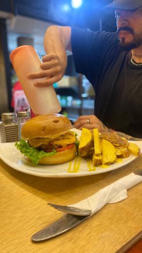 a man sitting at a table with a sandwich and french fries at Hostal La Guayunga RoofTop in Quito