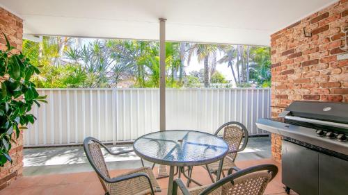 a patio with a table and chairs and a grill at Waterside Escape in Yamba