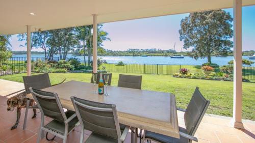 a table and chairs on a patio with a view of the water at Waterside Escape in Yamba