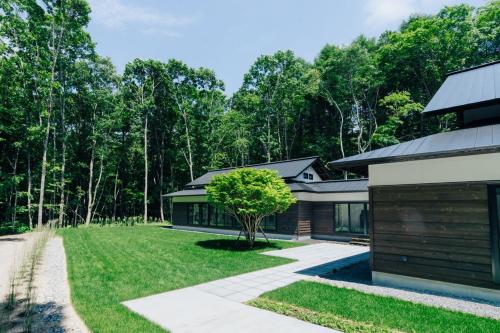 a house with a tree in the middle of a yard at 森のオーベルジュ 三 みつ - 旧 森厚真hotel CHUPKI - in Chitose