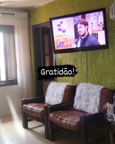 a living room with two couches and a flat screen tv at Pousada Atlântica stay home in Tramandaí