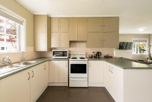 a kitchen with white cabinets and a white stove top oven at Averill Court Motel in Paihia