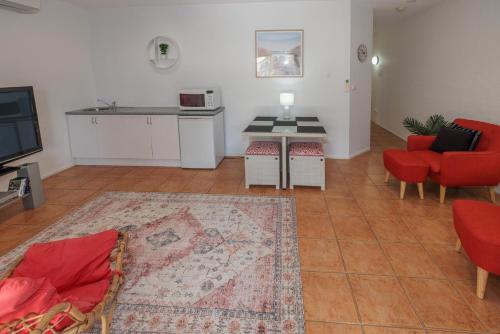 sala de estar con sillas rojas, mesa y cocina en Corlette Retreat, en Corlette