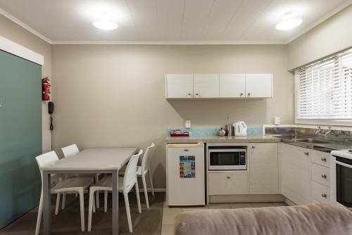 a kitchen with a table and a table and chairs at Averill Court Motel in Paihia