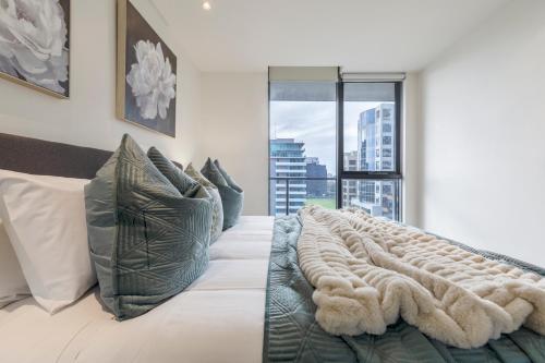 a bedroom with a large bed with a large window at Elegant City Fringe Condo w Pool & FREE Parking in Melbourne