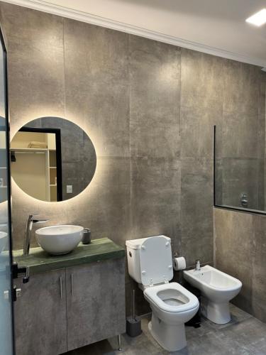 ein Badezimmer mit Toilette, Waschbecken und Spiegel in der Unterkunft Exclusive Dúplex Iguazú in Puerto Iguazú