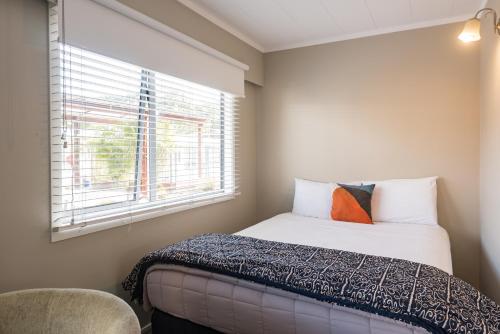 a bedroom with a bed and a window at Averill Court Motel in Paihia