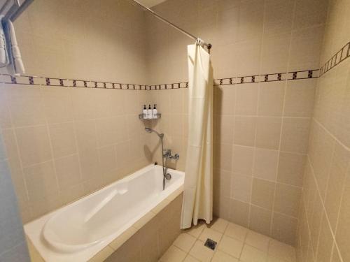 a bathroom with a tub and a shower and a sink at Whitewoods Convention and Leisure Hotel by SMS Hospitality in Silang