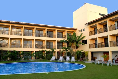 a hotel with a swimming pool in front of a building at Catussaba Business Hotel in Salvador