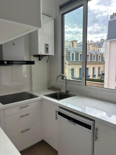une cuisine blanche avec un évier et une fenêtre dans l'établissement Room Iéna boissière, à Paris