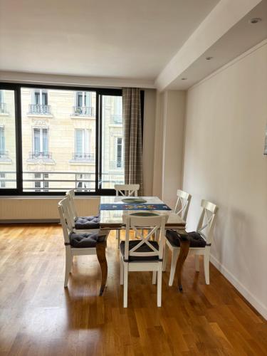 une salle à manger avec une table et des chaises et une grande fenêtre dans l'établissement Room Iéna boissière, à Paris
