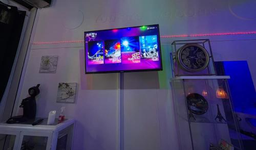 Elle comprend une télévision à écran plat murale avec une horloge. dans l'établissement Love room Paris, à Paris