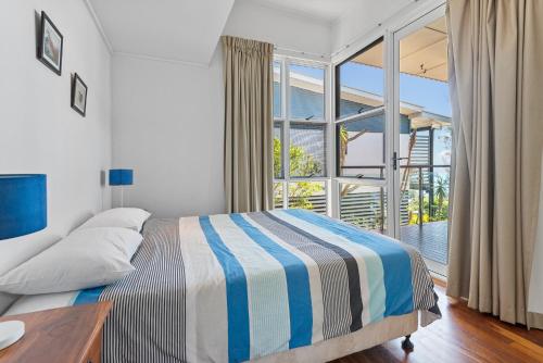 a bedroom with a bed and a large window at DOLCE VILLA in Tangalooma