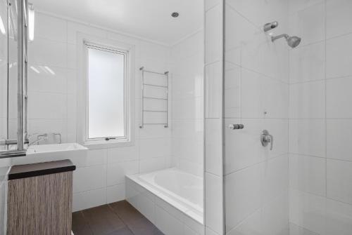 a white bathroom with a bath tub and a sink at DOLCE VILLA in Tangalooma