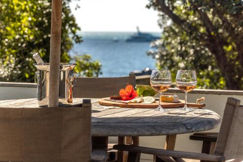 a wooden table with two glasses of wine on it at Onetangi Beach Pavilion -100 metres to Onetangi Beach! - Be My Guest Waiheke in Onetangi