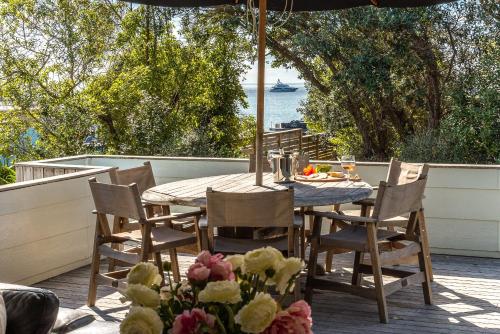 a table and chairs on a deck with an umbrella at Onetangi Beach Pavilion -100 metres to Onetangi Beach! - Be My Guest Waiheke in Onetangi
