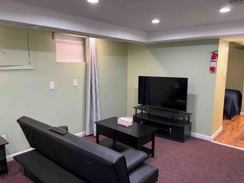 a living room with a couch and a flat screen tv at 1 Bedroom Basement, NEWLY Renovated in Bellerose Terrace