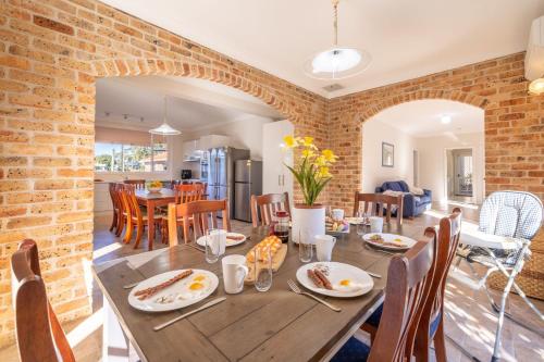 a dining room and living room with a table and chairs at Pet friendly 24 Irawari Crescent - pool, air con, boat parking in Nelson Bay
