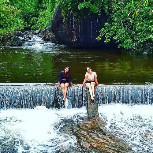 two women sitting on a wall over a waterfall at Forestscape Resort Munnar in Munnar