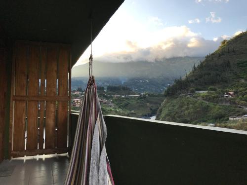 a hammock on a balcony with a view of a mountain at La Casa Verde Eco Guest House in Baños