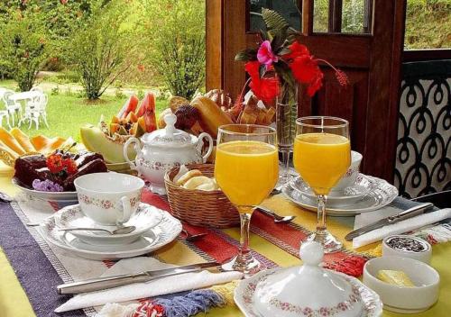 een tafel met een glas sinaasappelsap en een mand met eten bij Pousada Rio Dos Cristais in Visconde De Maua