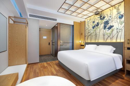 a bedroom with a white bed and a painting on the wall at Jingli Hotel - Beijing New National Exhibition Capital Airport in Houshayu