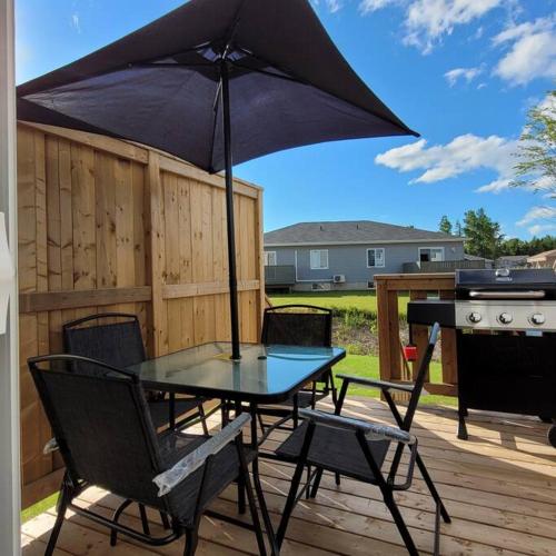 a table and chairs with an umbrella on a deck at The Owusu's Villa 1 in Dieppe