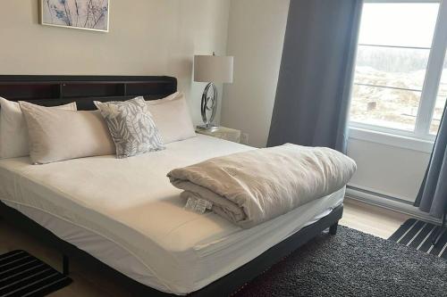 a bed with white sheets and pillows in a bedroom at The Owusu's Villa 1 in Dieppe