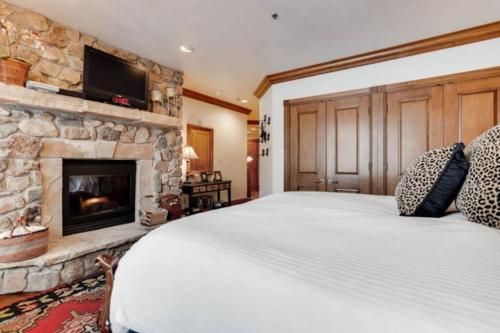 a bedroom with a bed and a stone fireplace at McCoy Peak 202 by East West Hospitality in Beaver Creek