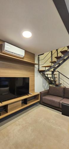 a living room with a couch and a tv and a staircase at Grand Loft - Amazing Duplex 314 in Sao Paulo
