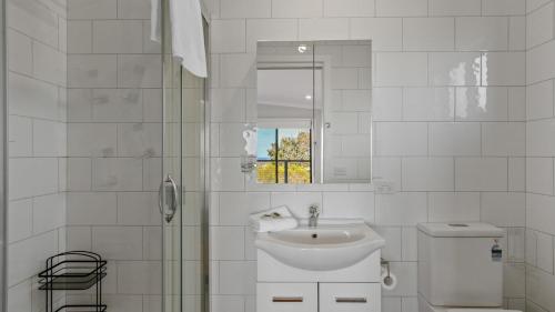 Un baño blanco con lavabo y ducha. en Anchored on Capes Upstairs, en Lakes Entrance
