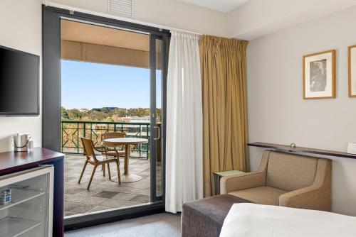 a hotel room with a bed and a balcony at Amora Hotel Riverwalk Melbourne in Melbourne