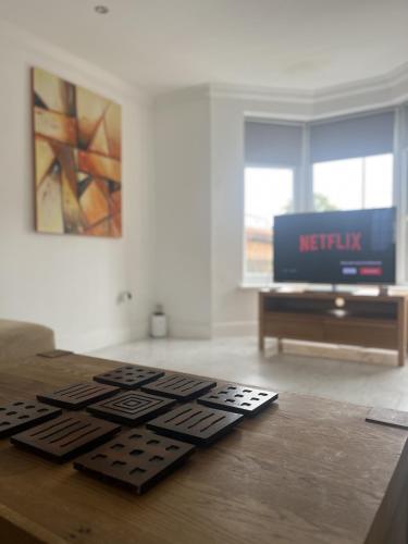 a living room with a television and a wooden table at The Spacious Stay Stratford in London