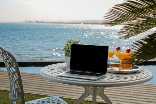 a laptop sitting on a table next to the water at 185 on BEACH Boutique Suites in Gordonʼs Bay