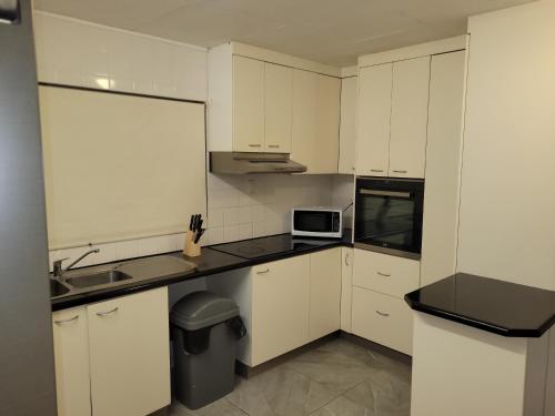 a white kitchen with a sink and a microwave at Paradise Holiday Apartments in Cairns