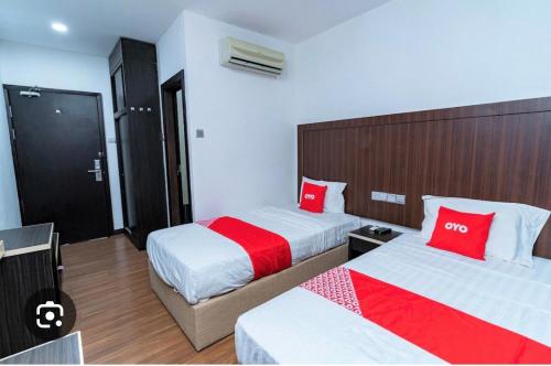 a hotel room with two beds with red pillows at Reggae Inn in Bintulu