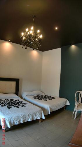 a bedroom with two beds and a chandelier at Hotel Casona del Truco in Guanajuato