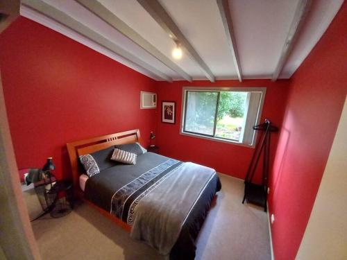 una camera da letto con pareti rosse e un letto con finestra di Homefield Cottage Halls Gap a Halls Gap