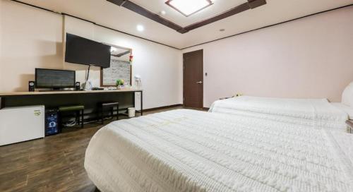 a bedroom with two beds and a desk with a television at Cheonan Terminal Comodo in Cheonan