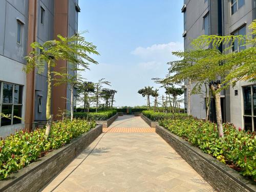 a walkway between two buildings with plants and trees at Gold Coast Apartment PIK Luxury Sea View by stay with E in Jakarta