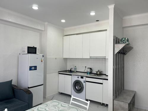 a kitchen with a refrigerator and a washing machine at Коттедж Green City Center in Chok-Tal