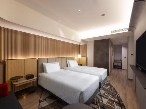 a hotel room with two beds and a television at Novotel Nara in Nara