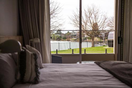 a bedroom with a bed and a large window at Nagambie Waterfront Motel in Nagambie