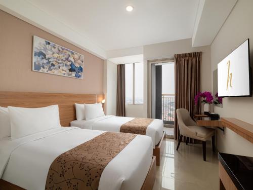 a hotel room with two beds and a desk at Horison Suite & Residences Iswara Bekasi in Rawapanjang