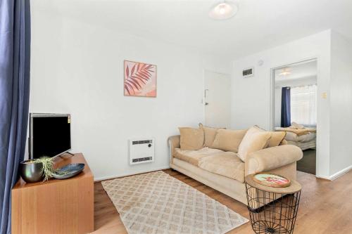 a living room with a couch and a tv at Spacious 1-Bedroom Apartment with Car Space in Melbourne