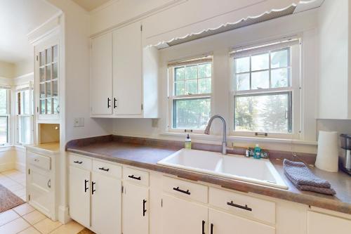 a kitchen with white cabinets and a sink at Flagpole Point in Phelps